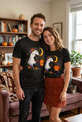Ghost Hugging Cat Pumpkin Halloween t-shirt — black Gildan G200 Ultra Cotton tee with a happy little ghost hugging a black cat wearing a dapper orange bow tie, a glowing jack-o-lantern, a crescent moon, and a ring of fall flowers